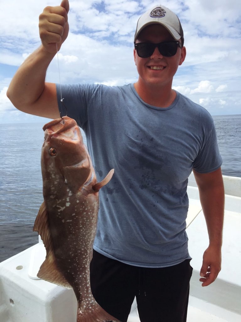Man holding fish one-handed on fishing charter at Anna Maria Island